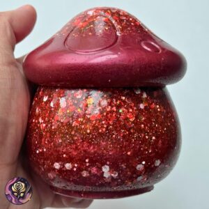 Handmade red glitter mushroom jar with lid, featuring a glossy finish and toadstool lid, perfect for trinkets or keepsakes.