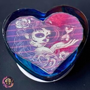 Heart-shaped resin phone grip with colorful sugar skull design in blue, purple, and pink, handmade and festive.