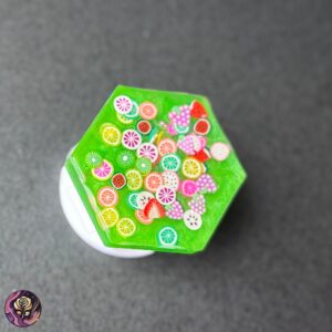 Hexagon resin pop socket with green base and miniature fruit slice accents including lemons, strawberries, and oranges.