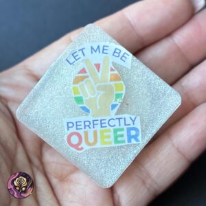 Handmade LGBTQ+ Rainbow Pop Socket with “Let Me Be Perfectly Queer” text, peace sign, and glitter resin on a square translucent phone grip