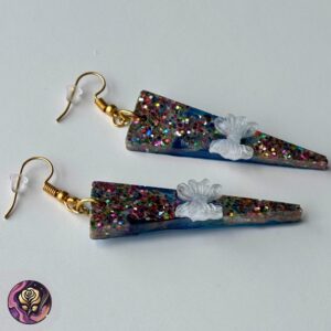 Handmade triangle-shaped resin earrings with chunky multicolor glitter and translucent white bow detail, displayed flat on a white background.