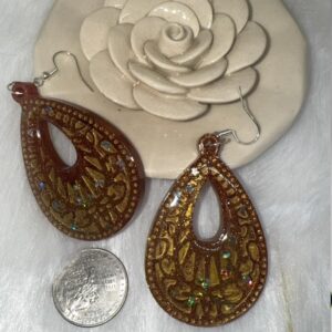Close-up of handmade gold resin teardrop earrings with star and moon glitter on stainless steel hooks