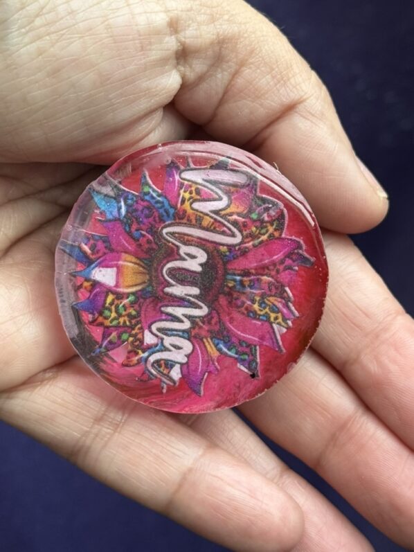 Mama resin phone grip with vibrant floral art, held in palm to show size and texture