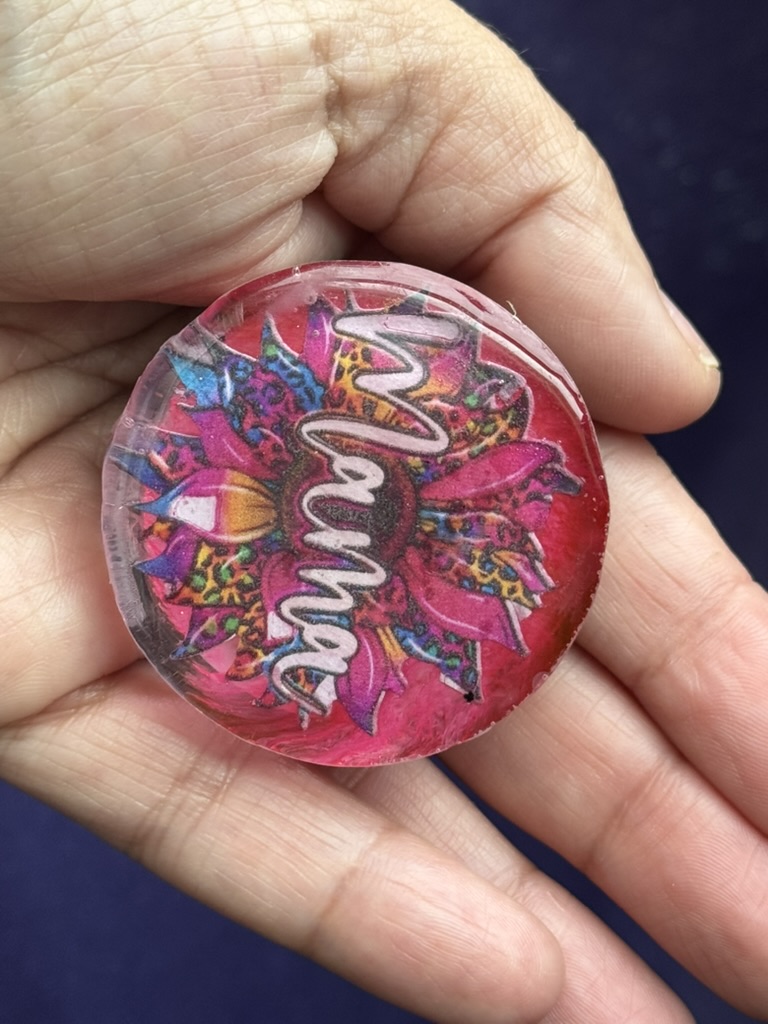 Mama resin phone grip with vibrant floral art, held in palm to show size and texture