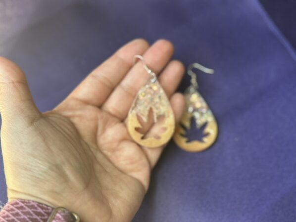 Lightweight resin leaf teardrop earrings shown in hand to highlight size, shape, and chunky glitter finish.
