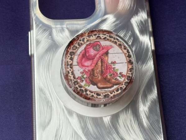 Close-up of cowgirl resin phone grip attached to phone case, highlighting rustic western detail