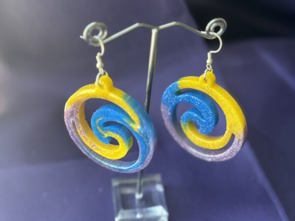 Pinwheel earrings hanging from display stand – bold resin dangles in yellow, blue, and purple glitter
