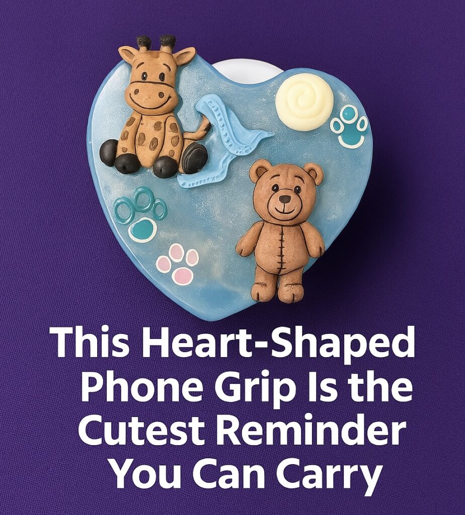 Heart-shaped resin phone grip in translucent blue with 3D teddy bear, giraffe, and floating paw prints on top, photographed on an orange background with white rose decor.