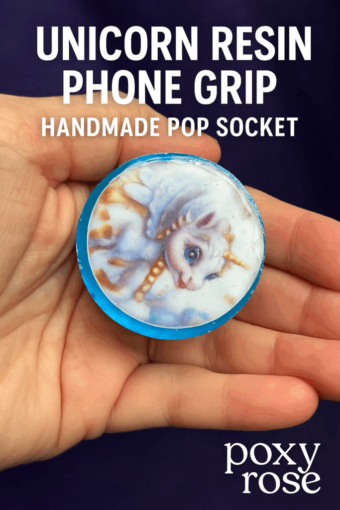 Hand holding a handmade unicorn resin phone grip with a blue border and glossy finish, set against a deep purple background. Bold white text reads 'Unicorn Resin Phone Grip – Handmade Pop Socket' with 'Poxy Rose' logo in the corner