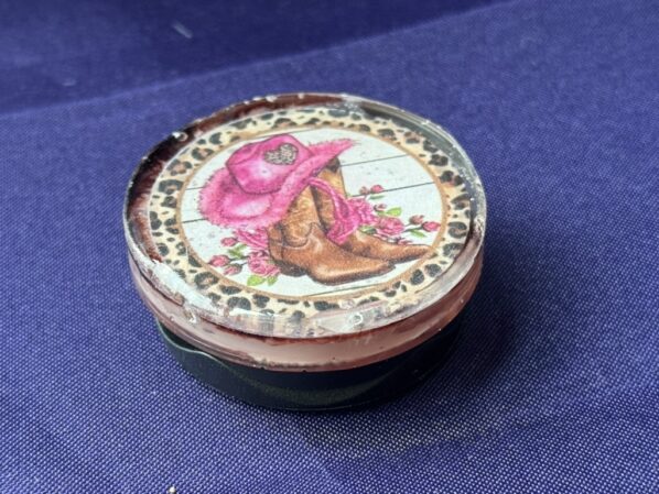 Side view of cowgirl resin phone grip showing glittery layered design and white grip base