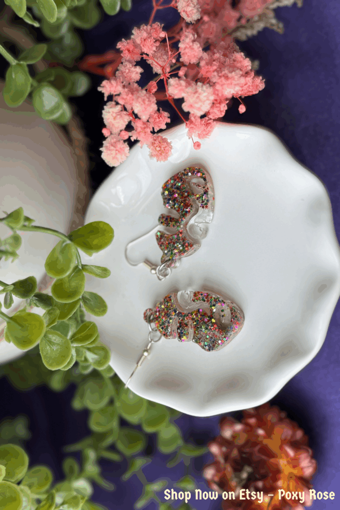 Multicolor glitter face resin earrings on white dish with florals
