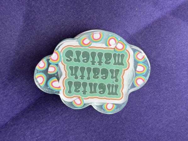 Resin cloud phone grip with rainbow accents and “Mental Health Matters” message, handmade and lightweight for daily use.